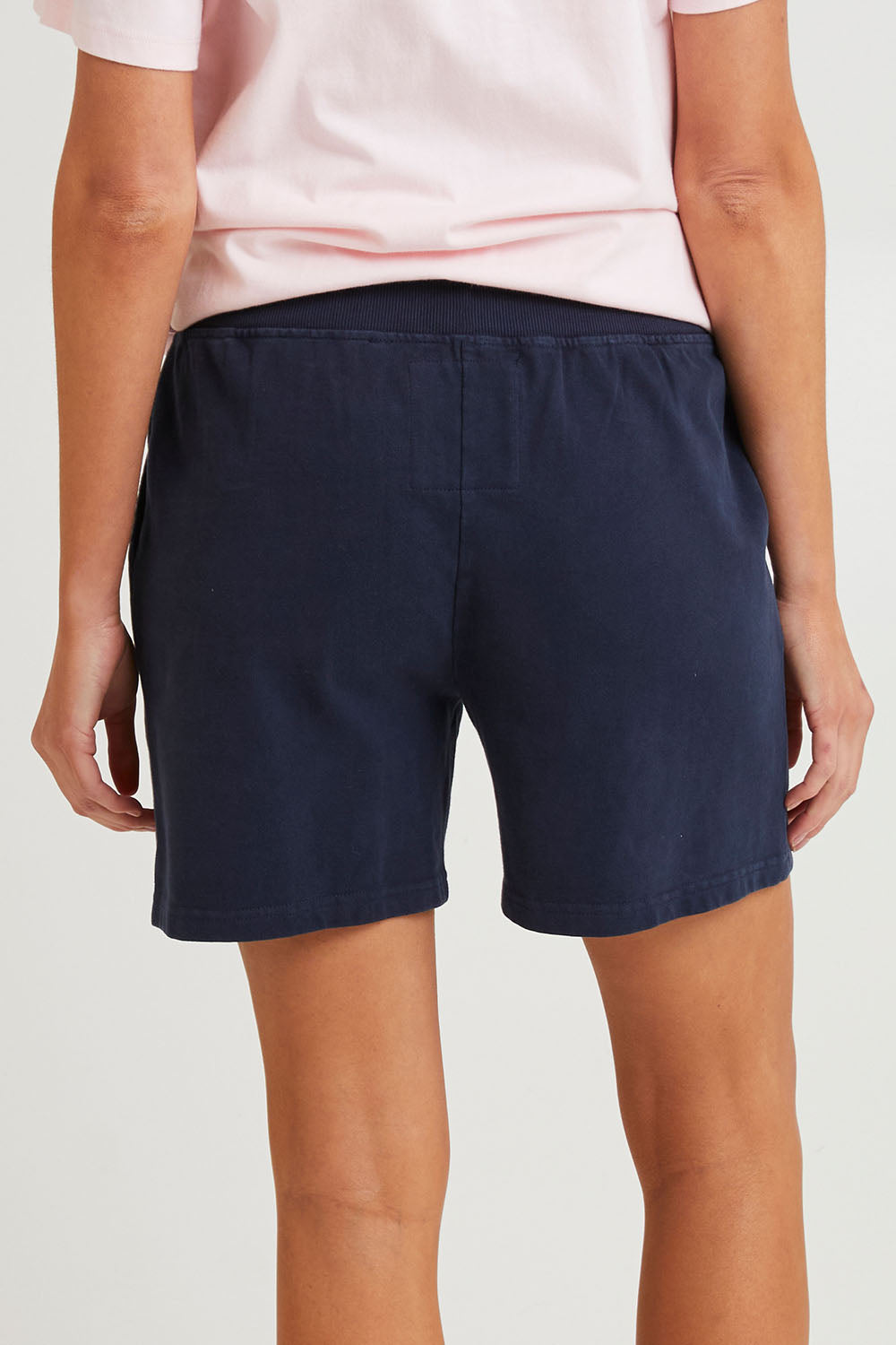 Model Madeline wearing size 10 of the Fundamental Elm Logo Short in colour Navy (Blue), from the back