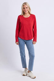 A model wearing the Fundamental Everyday Cotton Long Sleeve Tee in colour Cranberry (Red), from the front, showing the whole outfit