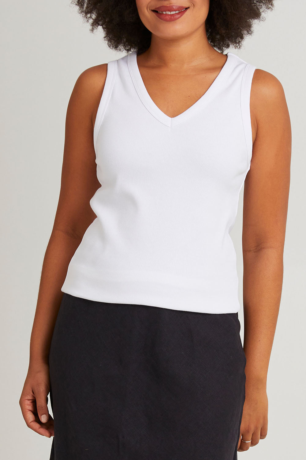 Model Olivia wearing size 10 of the Fundamental Rib Cotton Vee Tank in colour White (White), from the front, cropped image