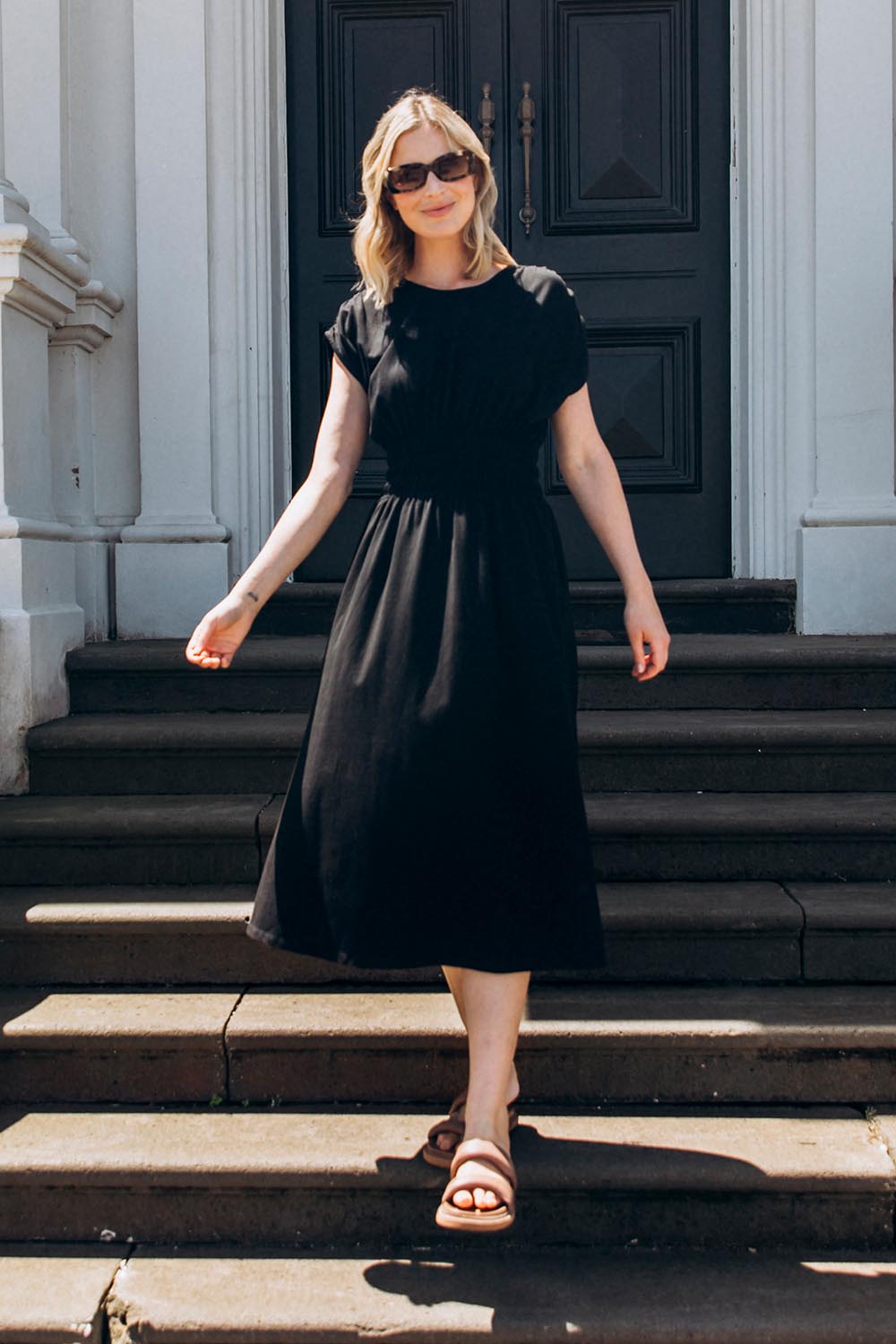 A model wearing the Fundamental Nelle Cotton Midi Dress in colour Black (Black), from the front, showing the whole outfit