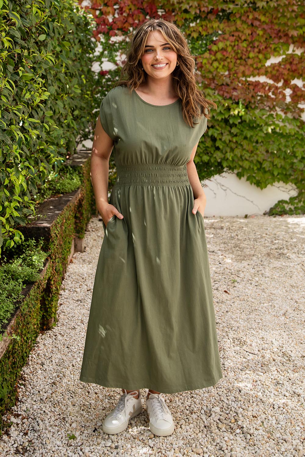 A model wearing the Fundamental Nelle Cotton Midi Dress in colour Clover (Green), from the front, showing the whole outfit
