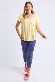 A model wearing the Fundamental Pima Cotton Vee Tee in colour Banana, from the front, showing the whole outfit