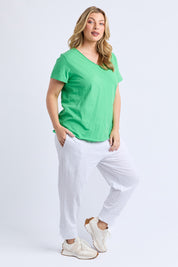A model wearing the Fundamental Pima Cotton Vee Tee in colour Springgree (Green), from the front, showing the whole outfit