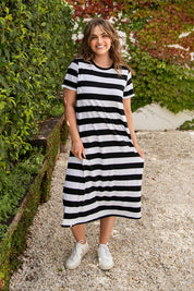A model wearing the Fundamental Adira Cotton Dress in colour Blackwhite (Black), from the front, showing the whole outfit