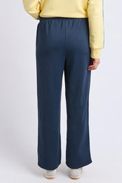 A model wearing the Fundamental Amara Trackpant in colour Navystripe (Blue), from the back