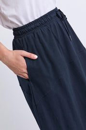 Model Genericm wearing size sample of the Fundamental Meadow Cotton Skirt – Navy in colour Navy, from an angle