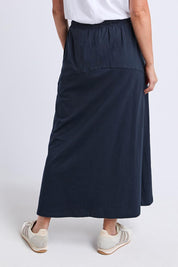 Model Genericm wearing size sample of the Fundamental Meadow Cotton Skirt – Navy in colour Navy, from the back