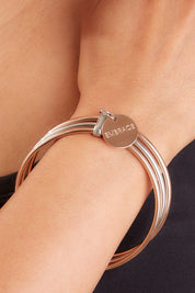 A model wearing the Triple Bangle Embracelet in colour Steel Rose (Metallics), from the front, showing the whole outfit