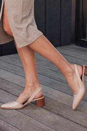 A model wearing the Aura Leather Heel in colour Nude, from the front, showing the whole outfit