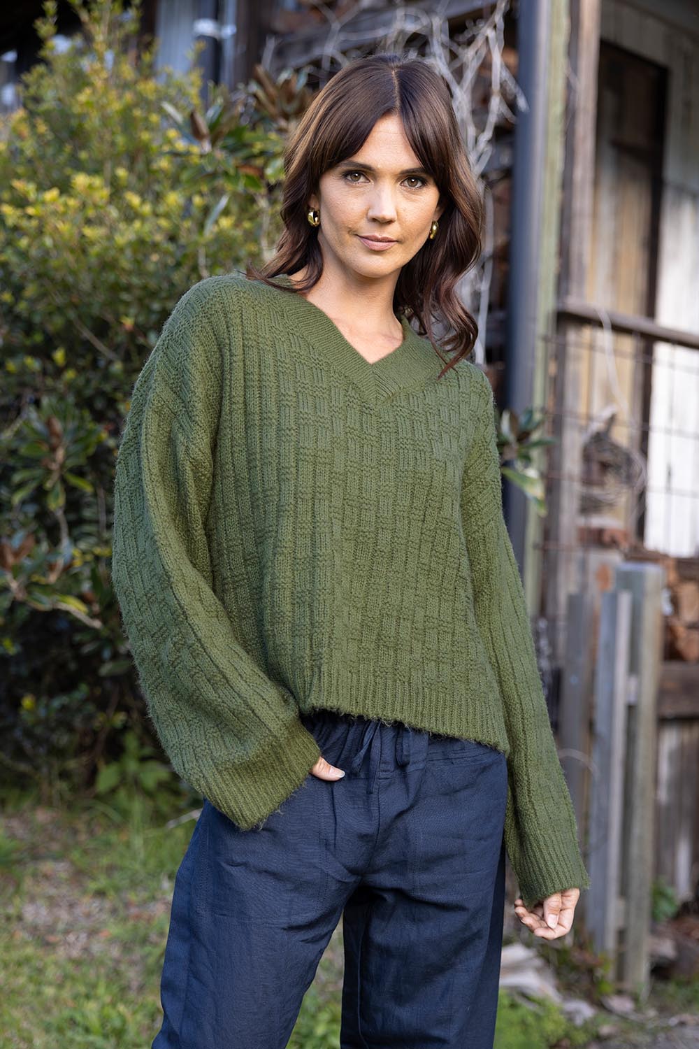 A model wearing the Knit V Neck Jumper in colour Olive (Green), from the front, showing the whole outfit