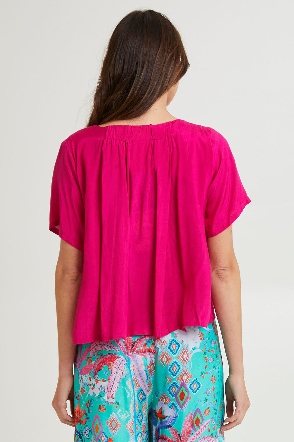 Model Madeline wearing size 10 of the Lux Essentials Top in colour Fushia (Pink), from the back