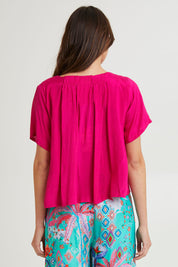 Model Madeline wearing size 10 of the Lux Essentials Top in colour Fushia (Pink), from the back