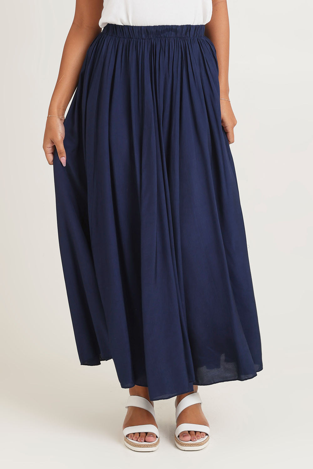 Model Ziara wearing size 10 of the Lux Crushed Maxi Skirt in colour Navy (Blue), from the front, cropped image