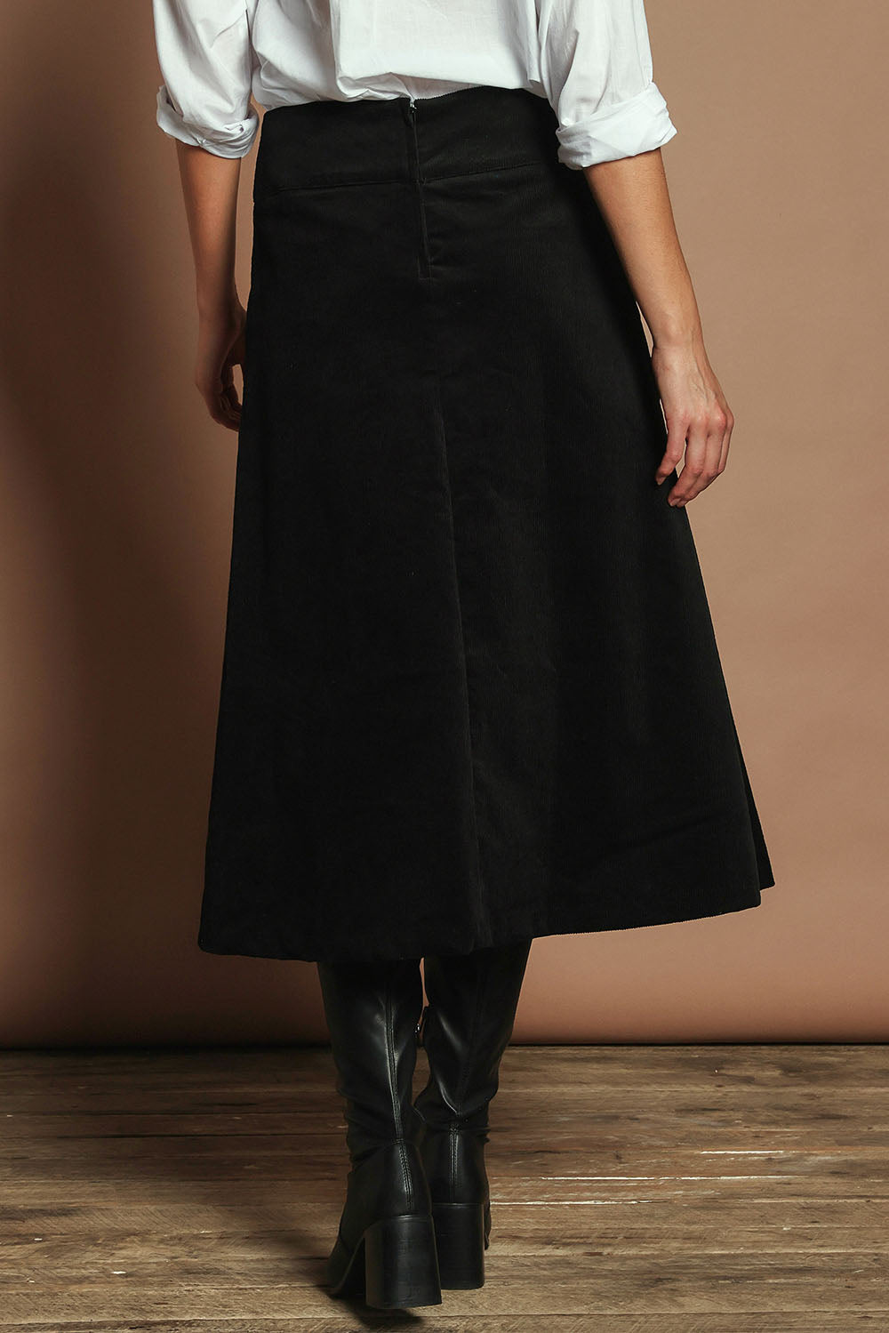 Model Madeline wearing size S of the Amy Cord Midi Skirt in colour Black (Black), from the back
