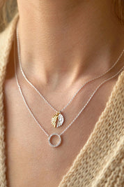 A model wearing the Wings Necklace in colour Silvergold (Metallics), from the front, cropped image