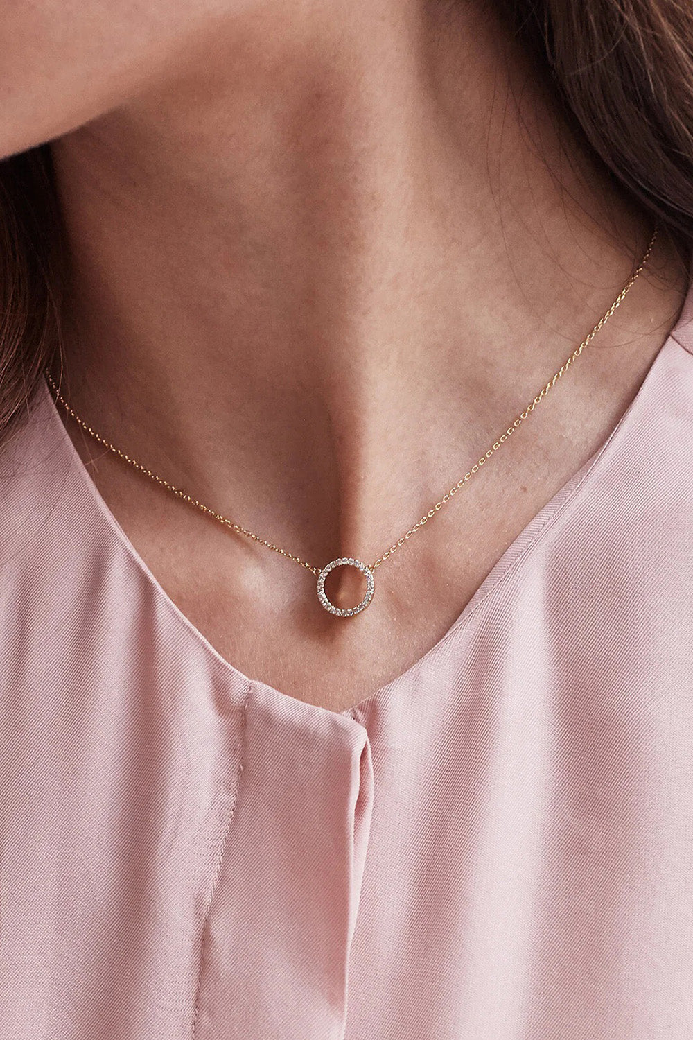 A model wearing the Circle Pave Necklace in colour Gold (Metallics), from the front, cropped image