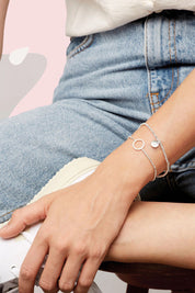 A model wearing the Louise Circle Bracelet in colour Silver (Metallics), from the front, cropped image