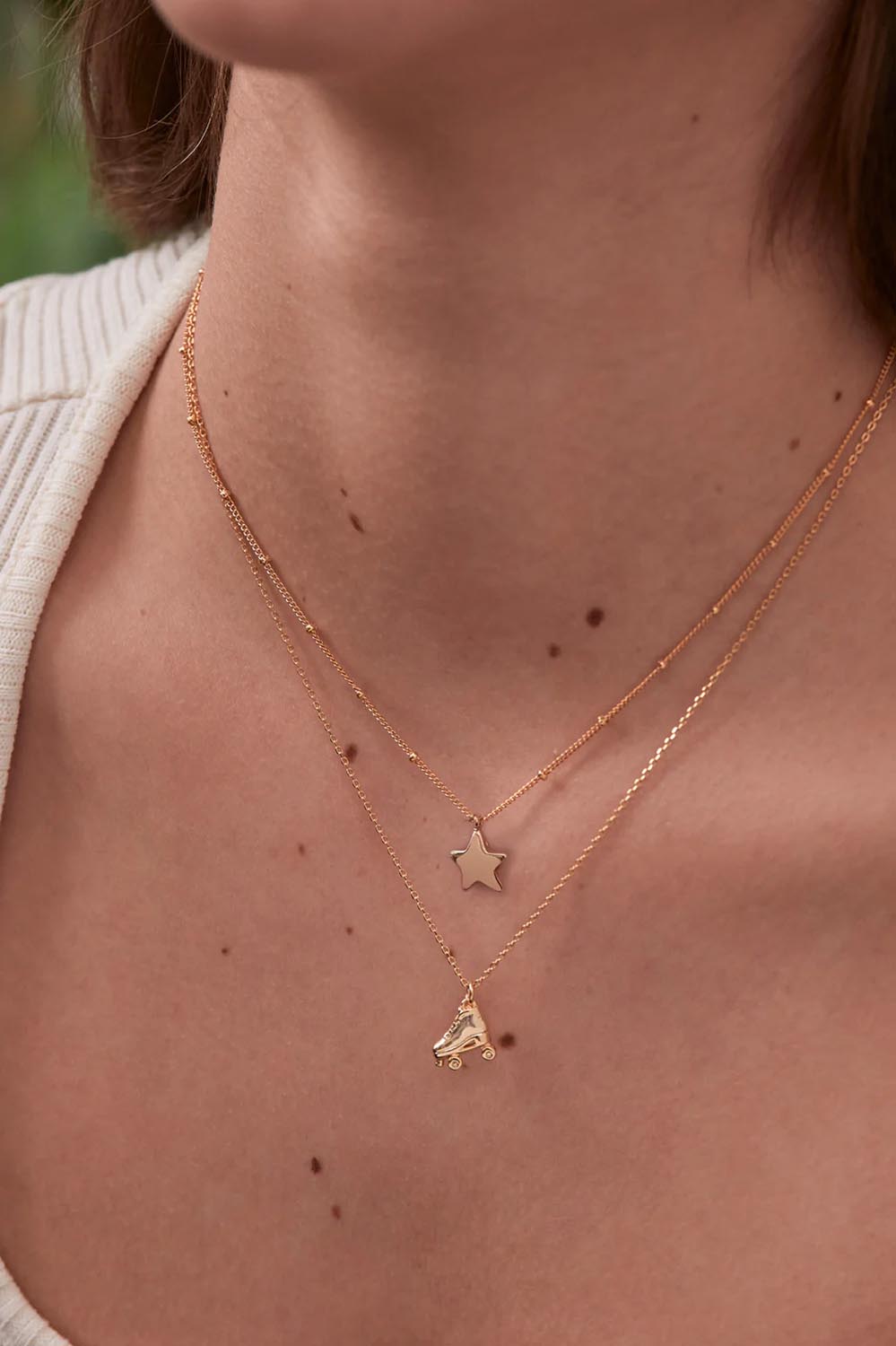 A model wearing the Hand Drawn Star Pendant On Beaded Chain in colour Gold (Metallics), from the front, cropped image