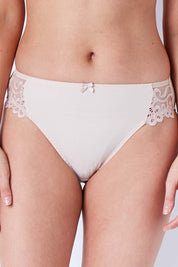 Model Phoebe wearing size S of the Coral High Cut Brief in colour Latte, from the front, cropped image