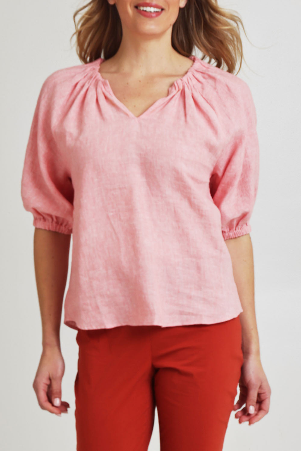 Model Olivia wearing size 10 of the Turn Up The Volume Top in colour Mellowpeac (Pink), from the front, cropped image