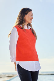 Model Alex wearing size S of the Chain Reaction Merino Vest in colour Squash, from the front, showing the whole outfit