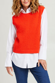 Model Emma wearing size S of the Chain Reaction Merino Vest in colour Squash, from the front, cropped image