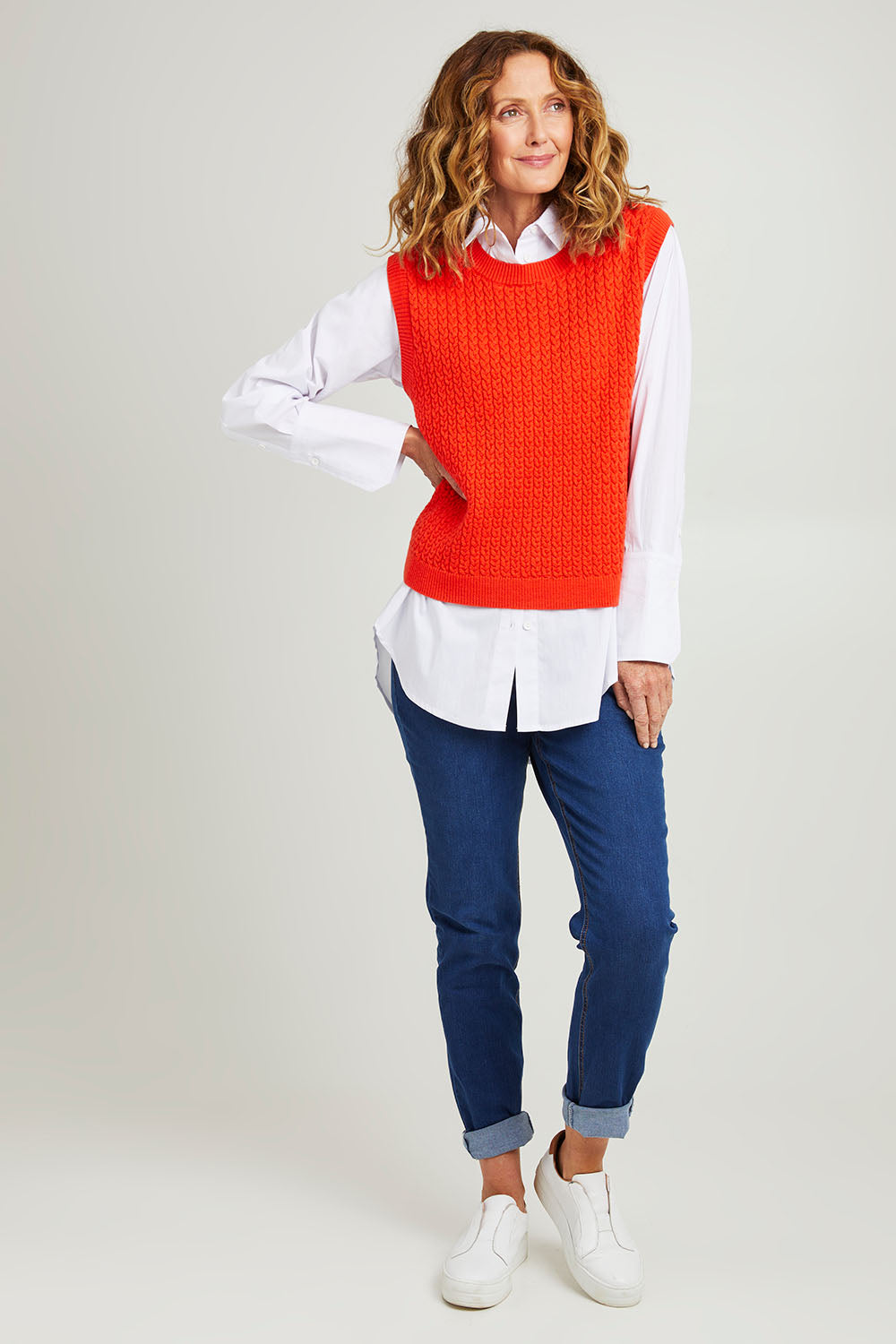 Model Emma wearing size S of the Chain Reaction Merino Vest in colour Squash, from the front, showing the whole outfit