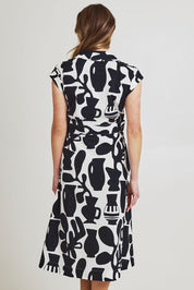 Model Olivia wearing size 10 of the Sew Chic Cotton Dress in colour Chalice (Black), from the back