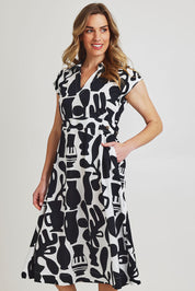 Model Olivia wearing size 10 of the Sew Chic Cotton Dress in colour Chalice (Black), from the front, cropped image