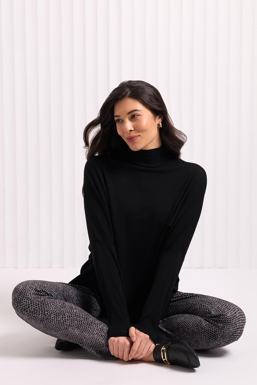 A model wearing the Merino Raisin The Baa Sweater in colour Black (Black), from the front, cropped image