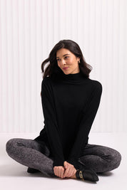 A model wearing the Merino Raisin The Baa Sweater in colour Black (Black), from the front, cropped image