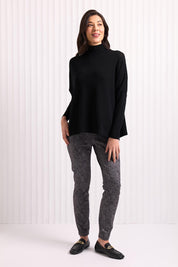 A model wearing the Merino Raisin The Baa Sweater in colour Black (Black), from the front, showing the whole outfit