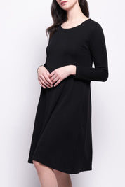 A model wearing the Merino Shear Delight Dress in colour Black (Black), from the front, cropped image