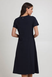 Model Madeline wearing size S of the Stitch Together Cotton Dress in colour Truenavy (Blue), from the back
