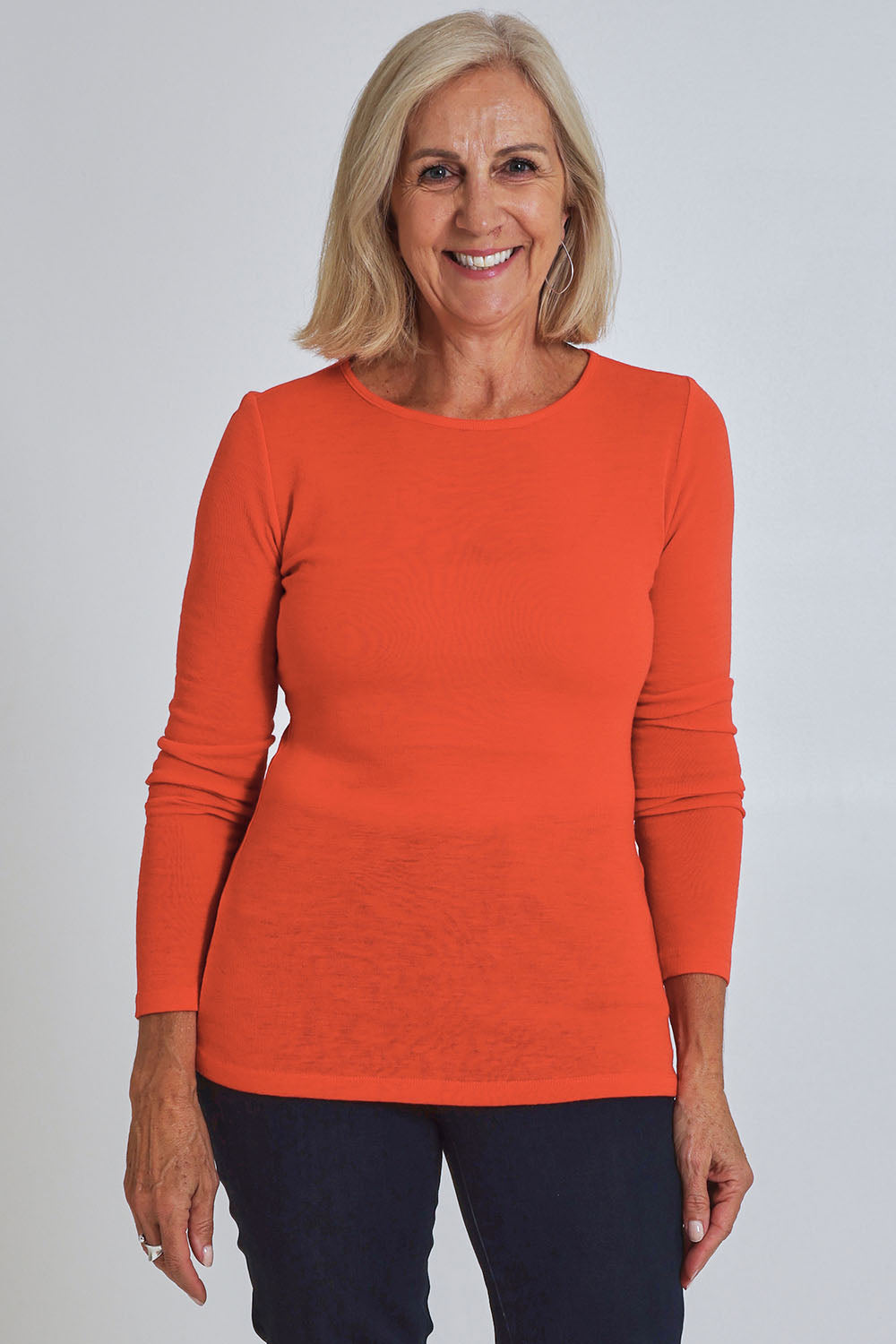 Model Sandy wearing size S of the Merino Signature Crew Top in colour Flash (Red), from the front, cropped image