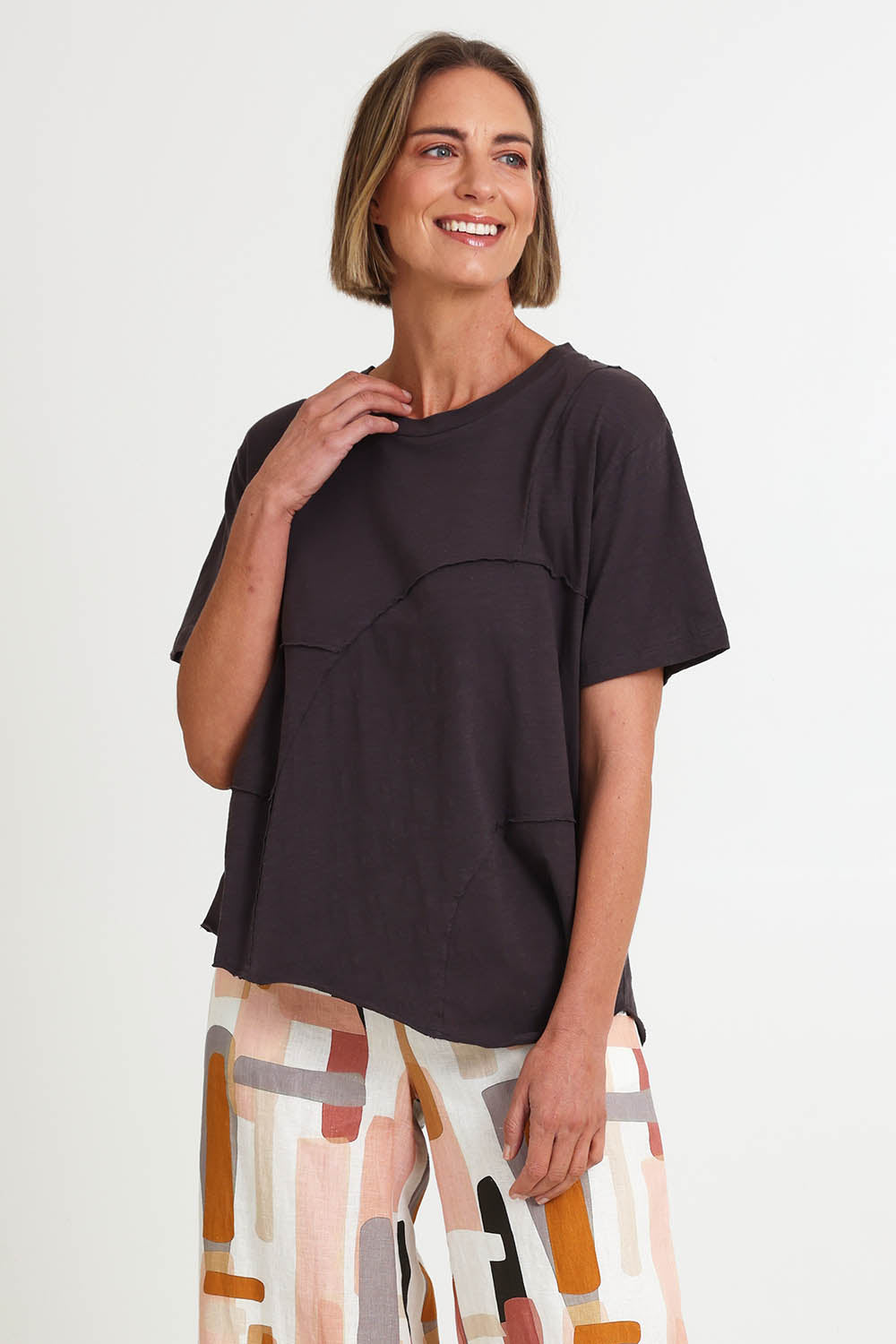 Model Riinar wearing size 10 of the Spliced And Diced Tee – Sable in colour Sable, from an angle