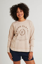 Model Grace wearing size 10 of the Leisure Medalion Crew in colour Oatmeal, from the front, cropped image