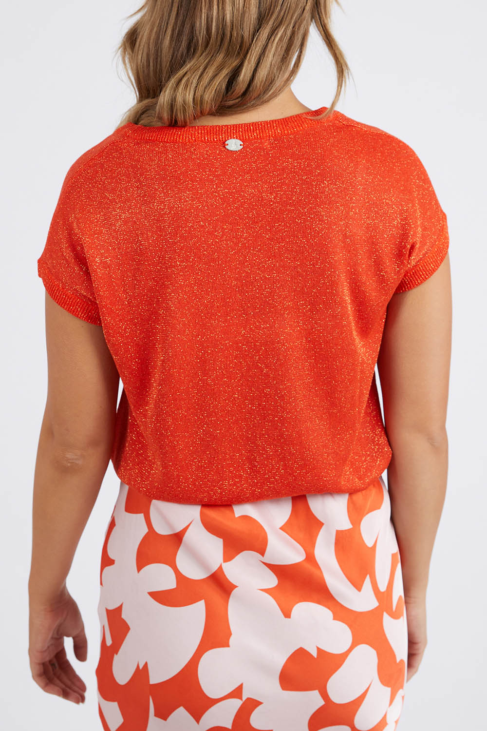A model wearing the Alma Metallic Knit in colour Spcyorange, from the back
