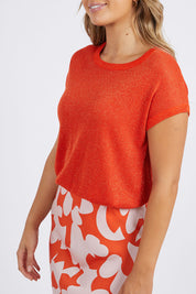 A model wearing the Alma Metallic Knit in colour Spcyorange, from the front, cropped image