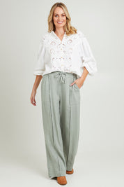 Model Grace wearing size 10 of the Naples Pant in colour Sage Green (Green), from the front, showing the whole outfit