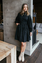 A model wearing the Goldie Dress in colour Black (Black), from the front, showing the whole outfit