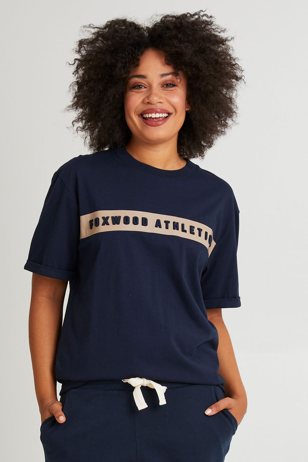 Model Olivia wearing size 10 of the Leisure Foxwood Athletics Tee in colour Navy (Blue), from the front, cropped image