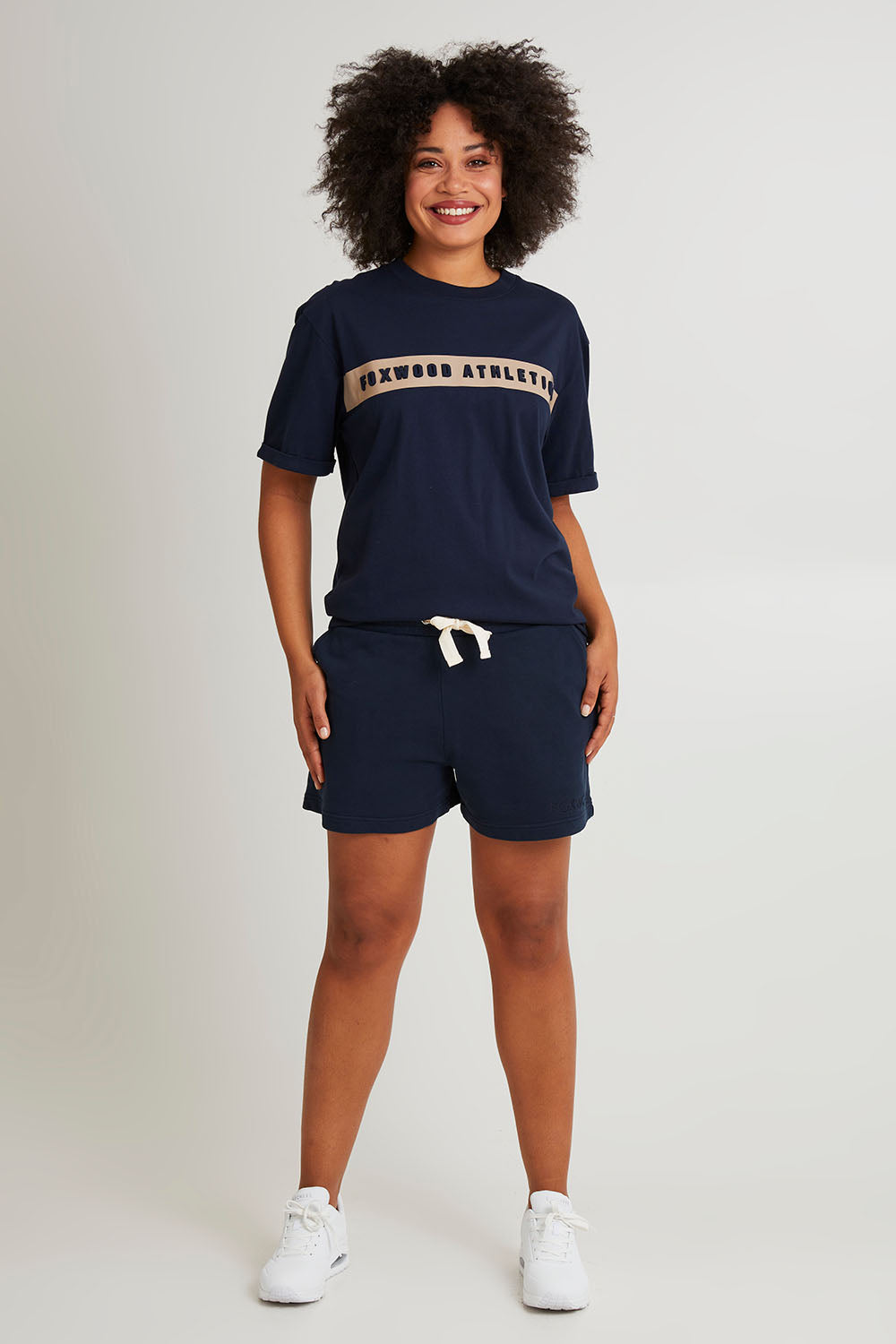 Model Olivia wearing size 10 of the Leisure Foxwood Athletics Tee in colour Navy (Blue), from the front, showing the whole outfit