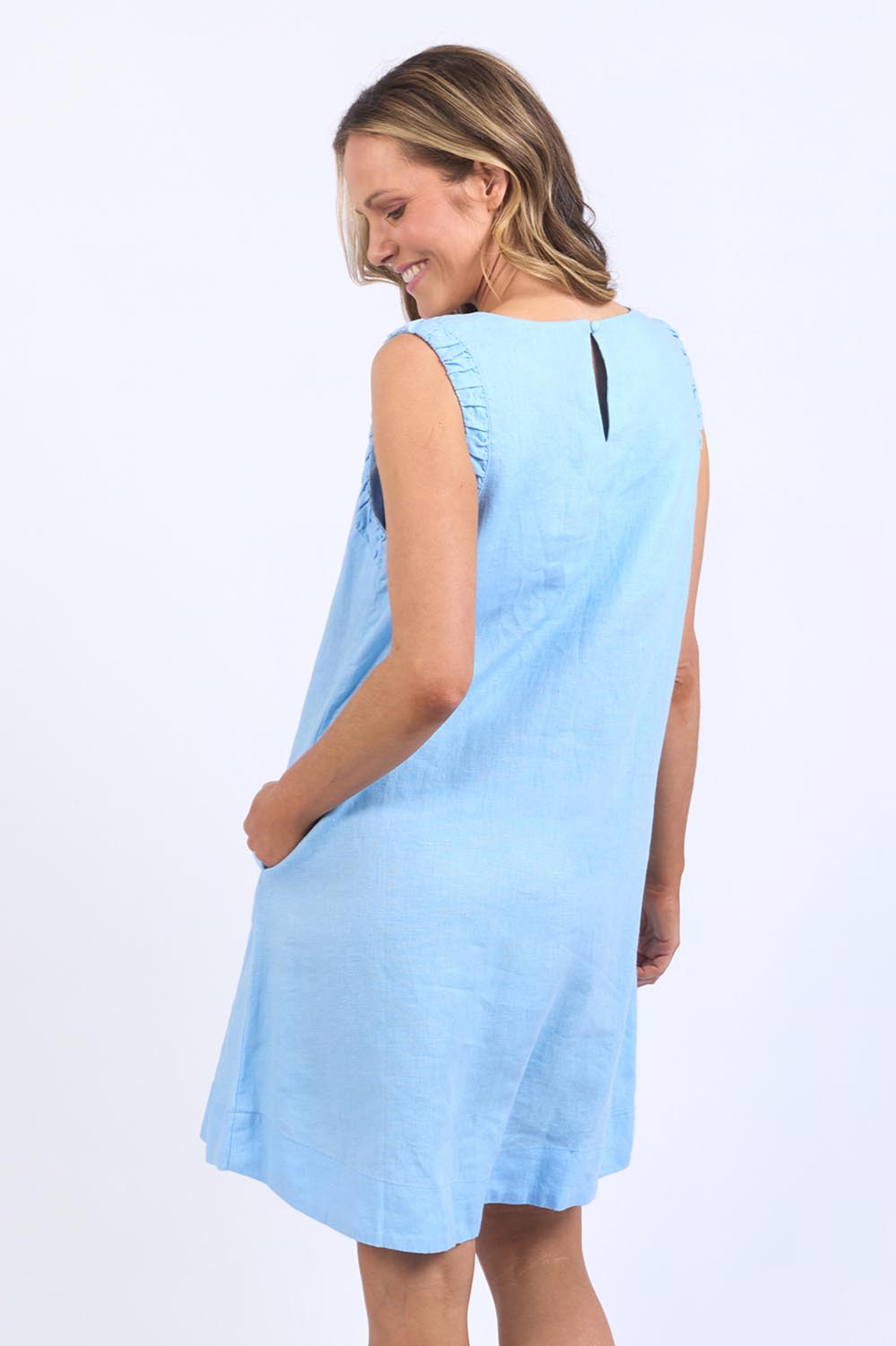 A model wearing the Bastia Linen Dress in colour Bluebelle (Blue), from the back