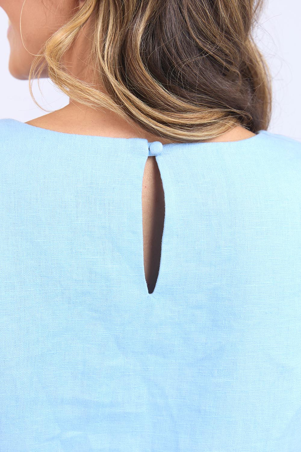 A model wearing the Bastia Linen Dress in colour Bluebelle (Blue), from the front, cropped image