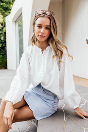 A model wearing the Corsica Blouse in colour Vinwhite (White), from the front, showing the whole outfit
