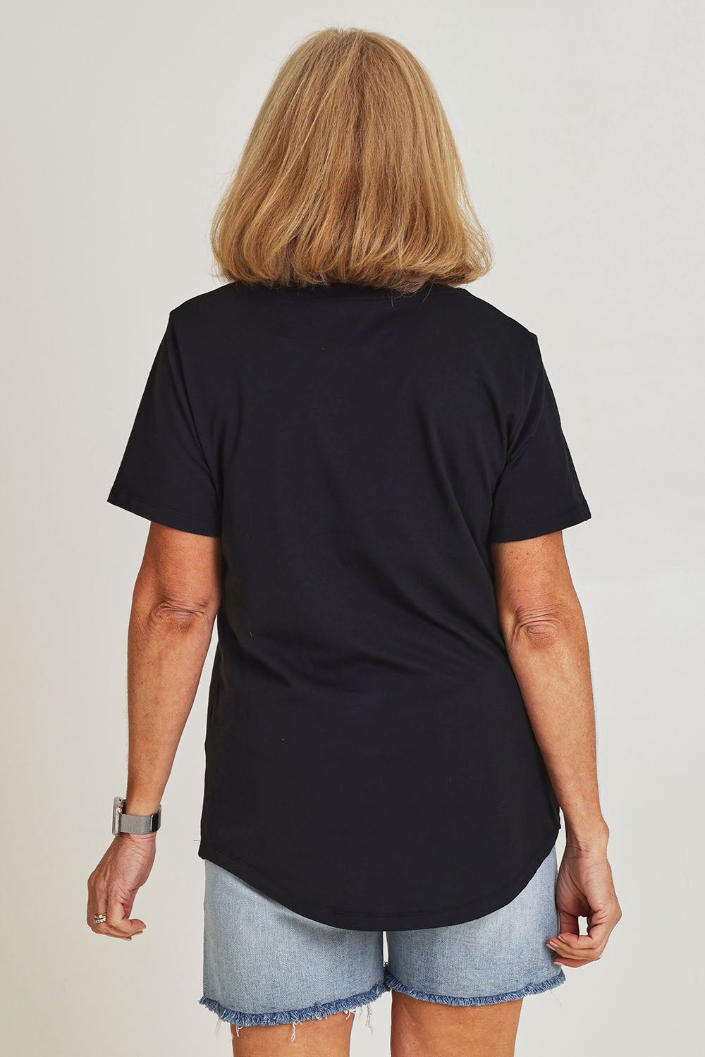 Model Sandy wearing size 10 of the Bloom Tee in colour Wshdblk (Black), from the back