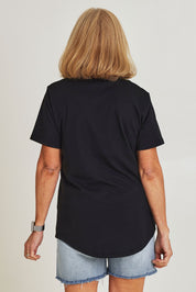 Model Sandy wearing size 10 of the Bloom Tee in colour Wshdblk (Black), from the back