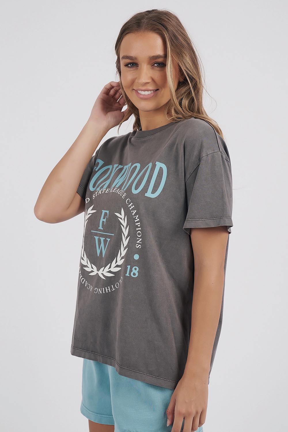 A model wearing the Leisure State League Tee in colour Iron (Grey), from the front, cropped image