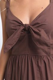 A model wearing the Esmerelda Cotton Dress in colour Chocolate, from the front, cropped image